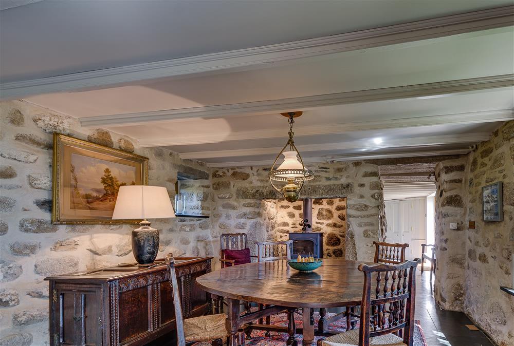 Dining room seating eight guests with exposed stone walls at Tregadjack Farmhouse, Tregathenan