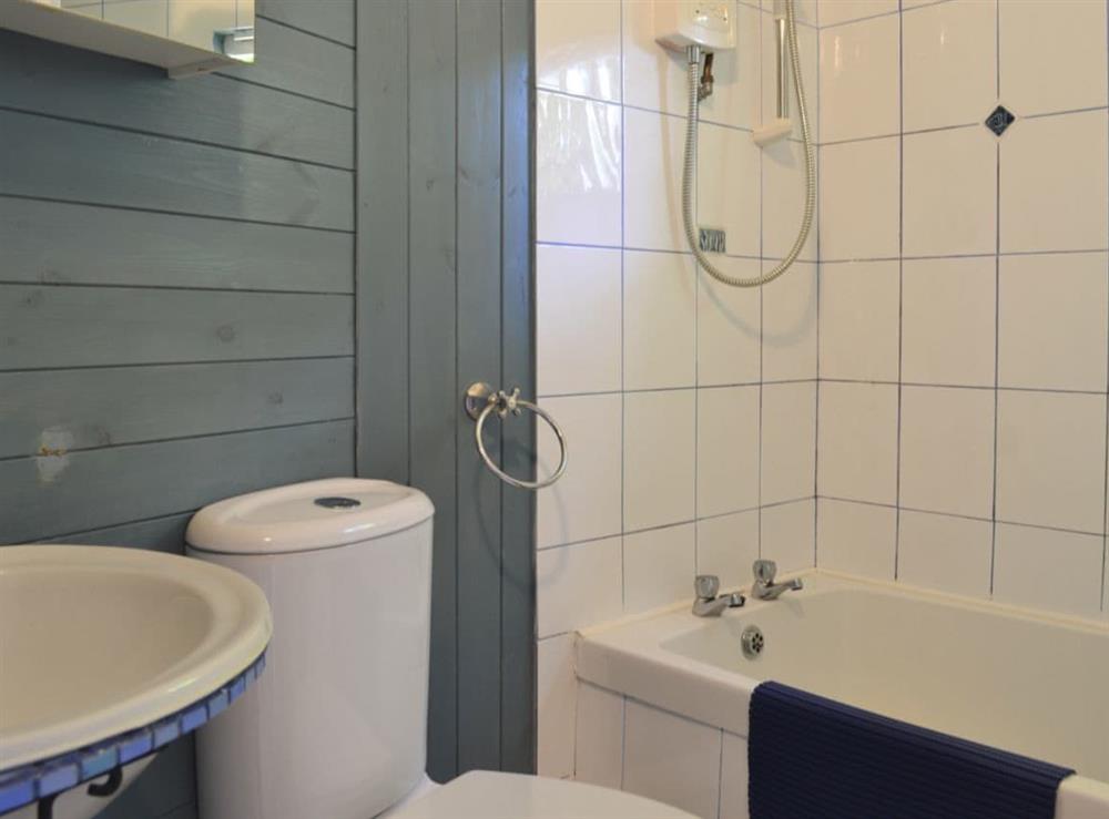 Bathroom with shower over bath, and toilet at Beach Retreat, 