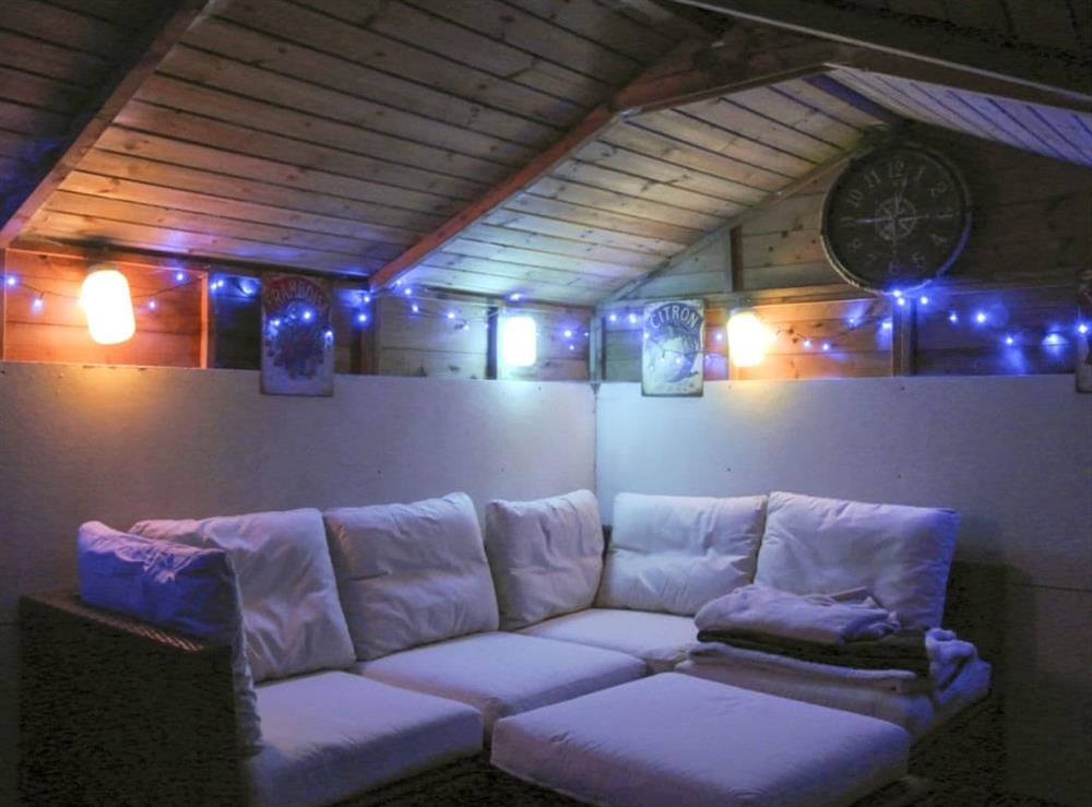 Cosy summer house with an L-shaped sofa and lights (photo 2) at Trevellyan Barn in St Austell, Cornwall