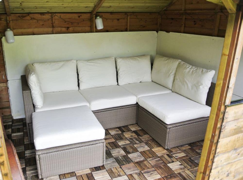 Cosy summer house with an L-shaped sofa and lights at Trevellyan Barn in St Austell, Cornwall