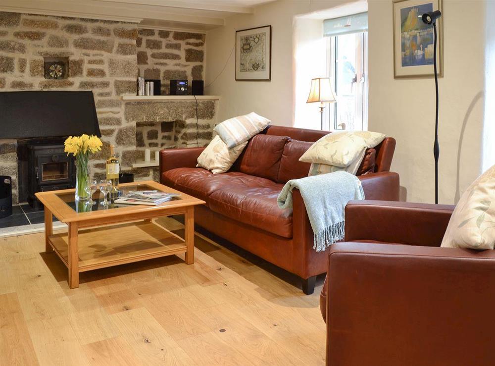 Living room with wood burner & wooden flooring at Treveth Cottage in Lamorna, near Penzance, Cornwall, England