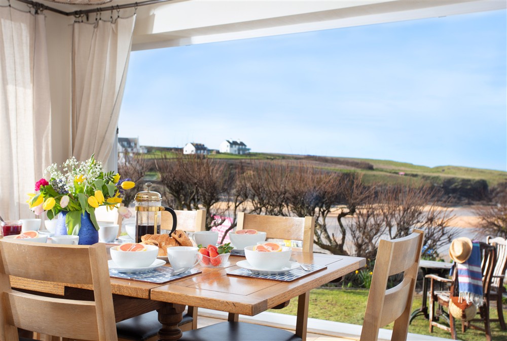 Large dining table for up to eight guests with beautiful view of Treyarnon Bay at Trewalder, Treyarnon Bay, St Merryn