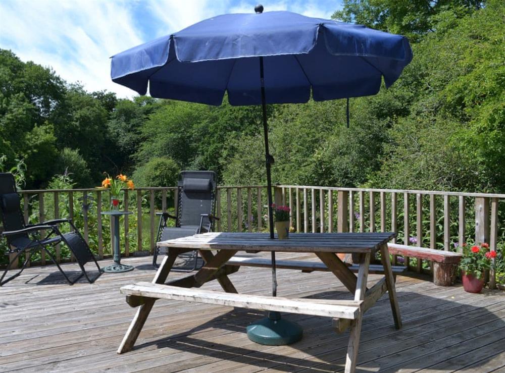 Enjoy an alfresco meal on the decking overlooking the lake and grounds at Tulip Lodge in Tideford Cross, near Saltash, Cornwall
