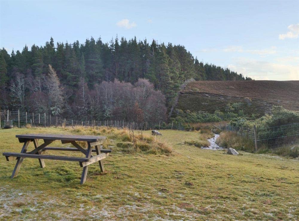 Picnic style seating in the garden with fantastic views over the surrounding countryside at Turin Nurin Cottage in Tomatin, near Inverness, Inverness-Shire