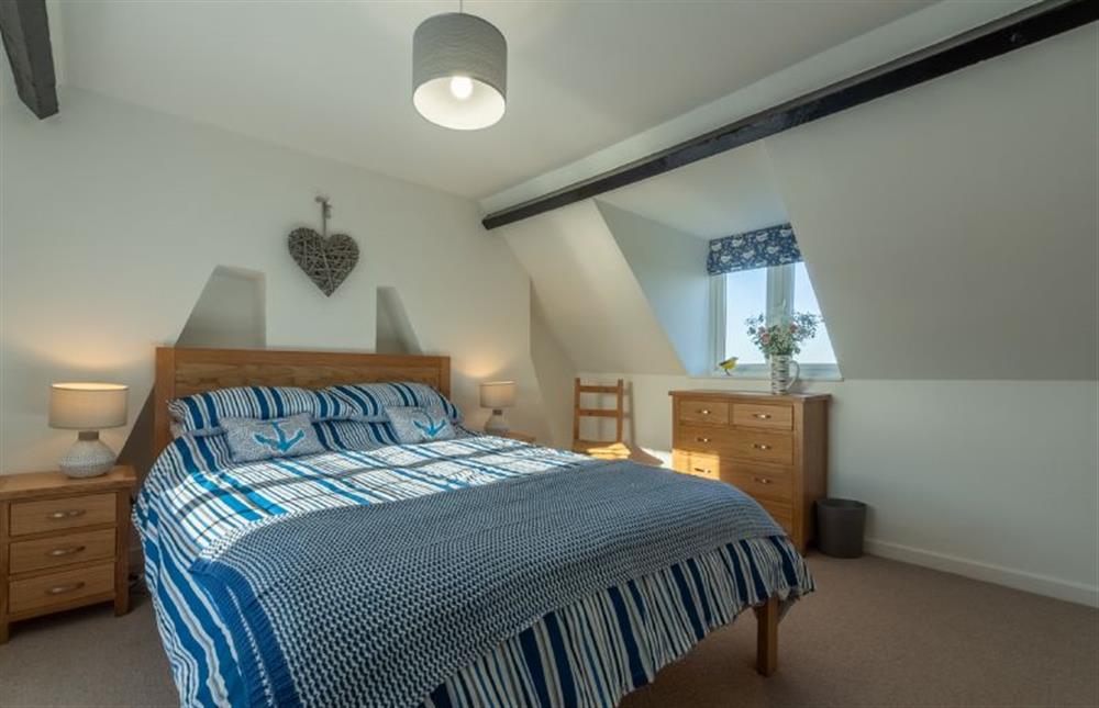 Second floor: King-size bedroom with apex beamed ceiling and dual aspect windows at Twitchers Cottage, Titchwell near Kings Lynn