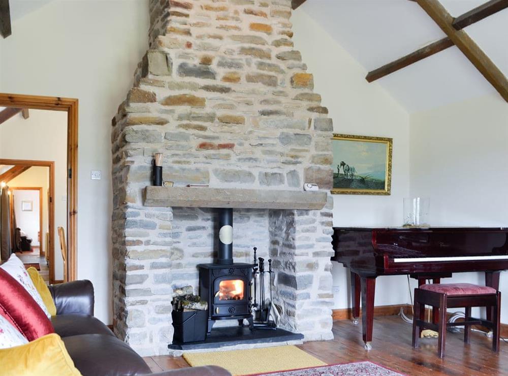 Impressive stone fireplace and piano in the living room at Ty Hir in Pontyates, near Kidwelly, Dyfed