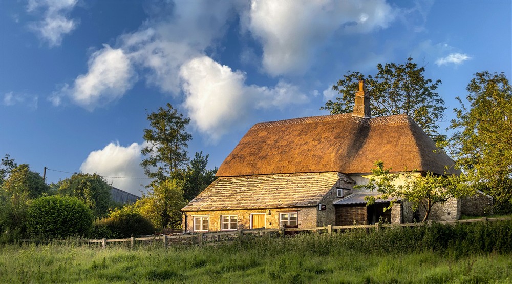 The exterior of Vineyard Farm Cottage, a stone cottage with thatched roof, Dorset (photo 2) at Vineyard Farm Cottage in Wareham, Dorset