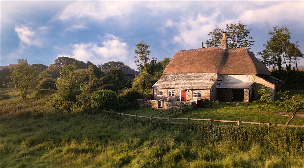 The exterior of Vineyard Farm Cottage, a stone cottage with thatched roof, Dorset (photo 3) at Vineyard Farm Cottage in Wareham, Dorset
