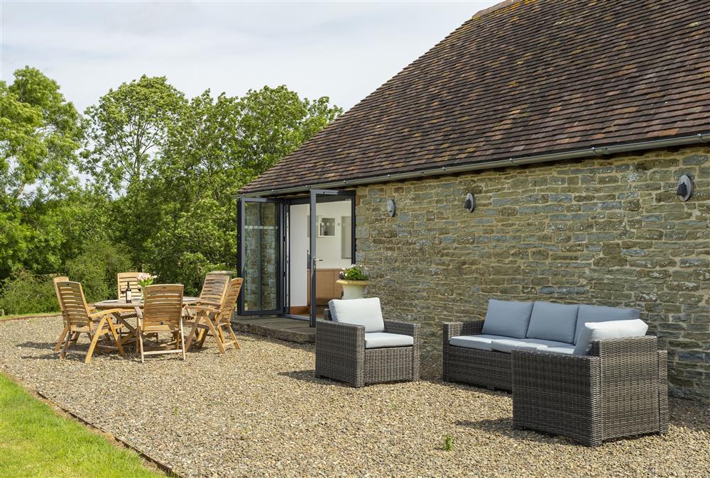 Outdoor seating area with wooden table and chair set and additional rattan garden furniture at Wassell Barn, Craven Arms