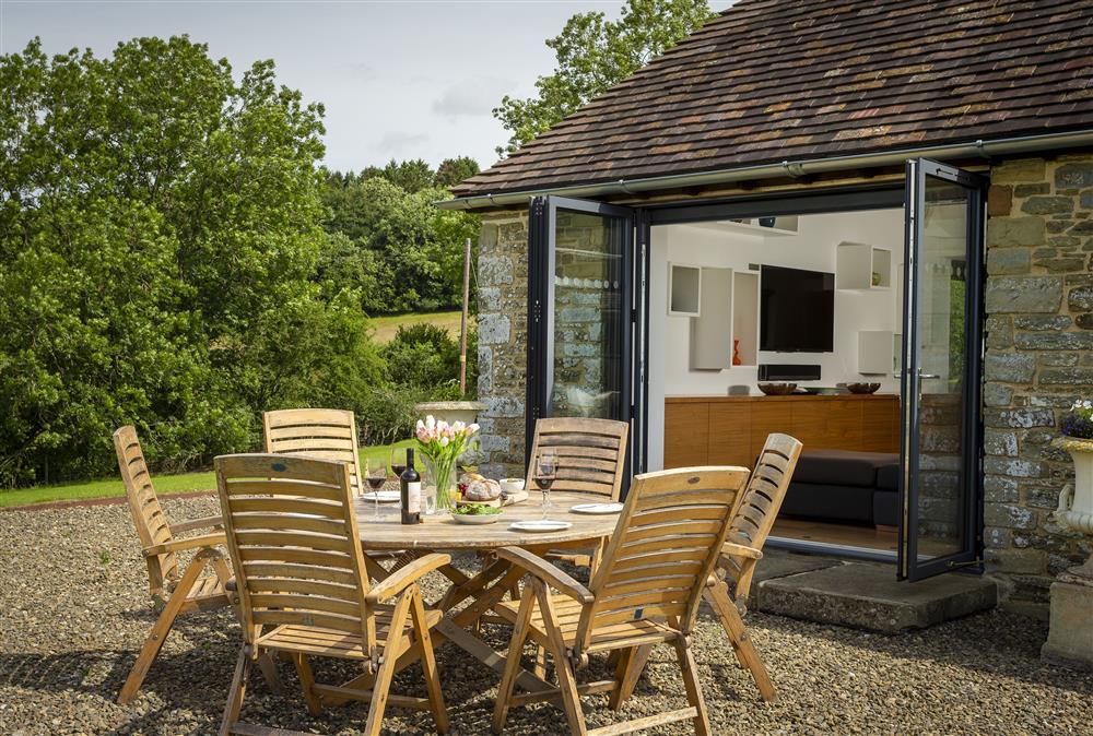 Outdoor seating area with wooden table and chair set at Wassell Barn, Craven Arms