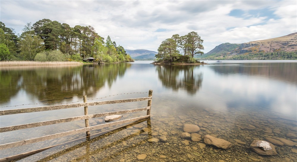 Looking across to Otter Island from the banks of Derwent Water on a cloudy spring day at Watendlath Bothy in Keswick, Cumbria