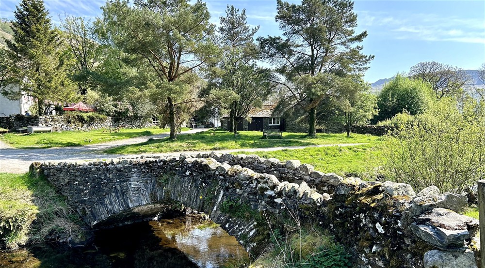 Looking over the stream and grassy bank towards Watendlath Bunkhouse, Cumbria at Watendlath Bothy in Keswick, Cumbria