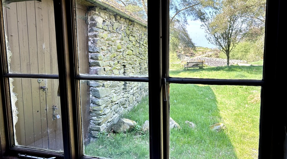 The view from Watendlath Bunkhouses window, showing the stone bridge crossing the nearby stream, Cumbria at Watendlath Bothy in Keswick, Cumbria