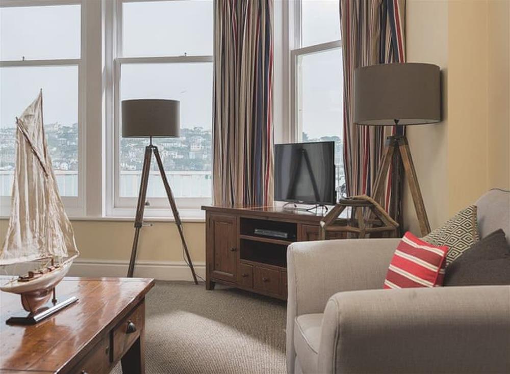 The spacious sitting room is comfortably furnished and has large south facing windows with views of the harbour and open sea at Waterfront Apartment in Fowey, Cornwall