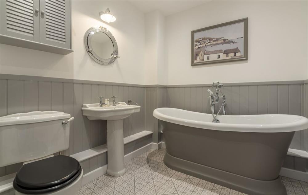 En-suite bathroom with freestanding roll-top bath and hand-held shower attachment at Wedge Cottage, Roserrow