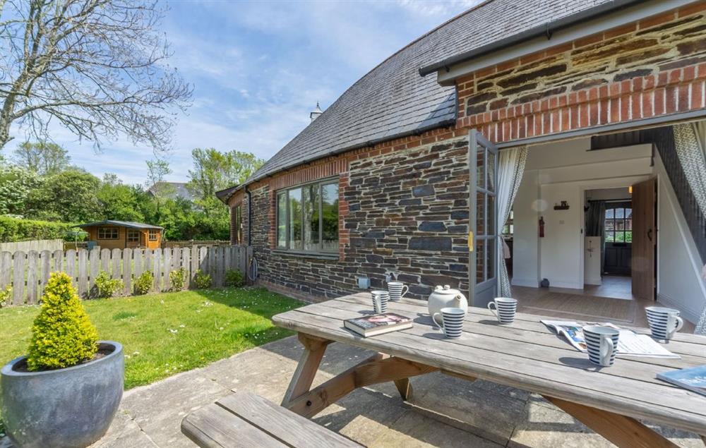Enclosed patio and garden with charcoal barbecue and picnic table at Wedge Cottage, Roserrow