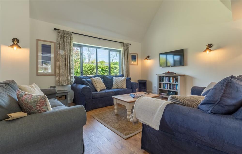 Spacious sitting area with comfortable sofas and wall mounted television at Wedge Cottage, Roserrow