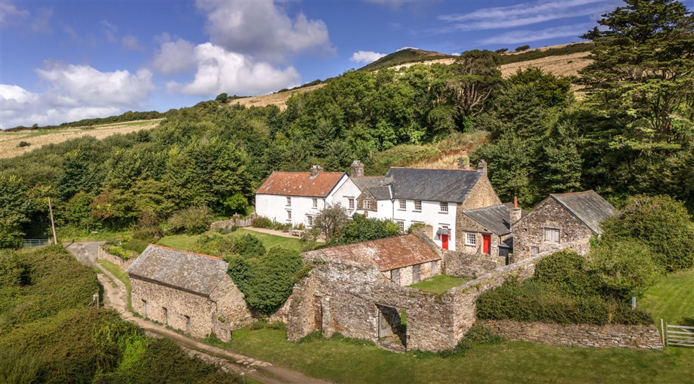 An aerial view of West Challacombe Manor and Cottage, including the grassy courtyard which takes you to the main entrance of the manor, Devon at West Challacombe Manor in West Exmoor, Devon