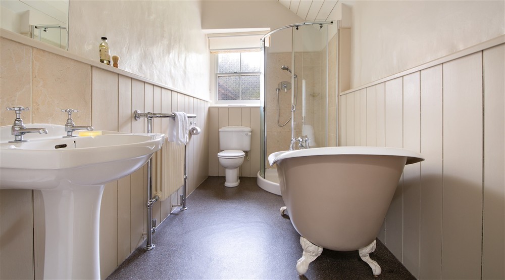 The bathroom with roll-top bath and freestanding shower at West Challacombe Manor in West Exmoor, Devon