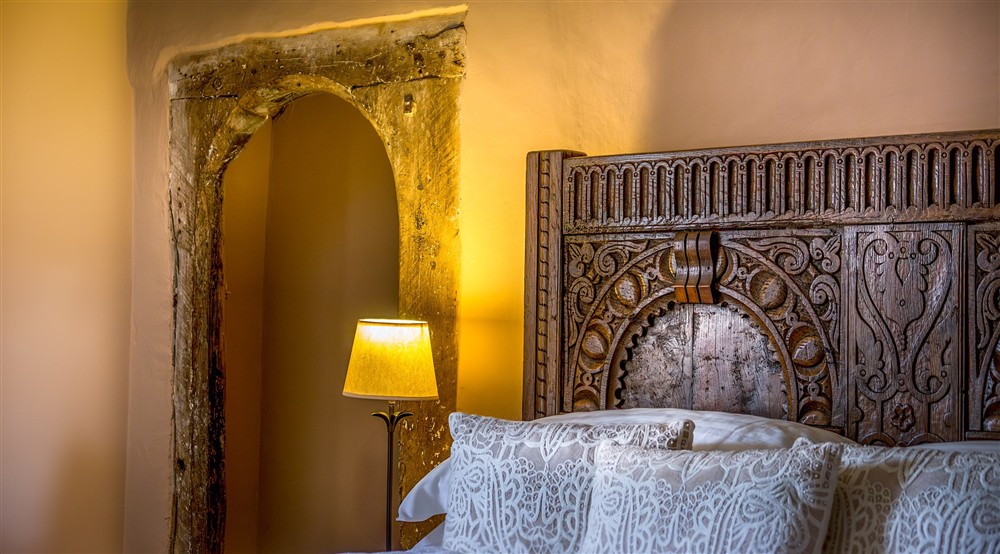 The carved wooden headboard and alcove with original wooden frame in the double bedroom at West Challacombe Manor in West Exmoor, Devon