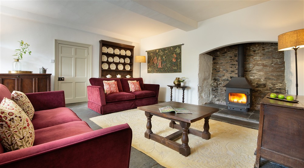 The ground-floor sitting room, with inglenook and woodburner, at West Challacombe Manor in West Exmoor, Devon