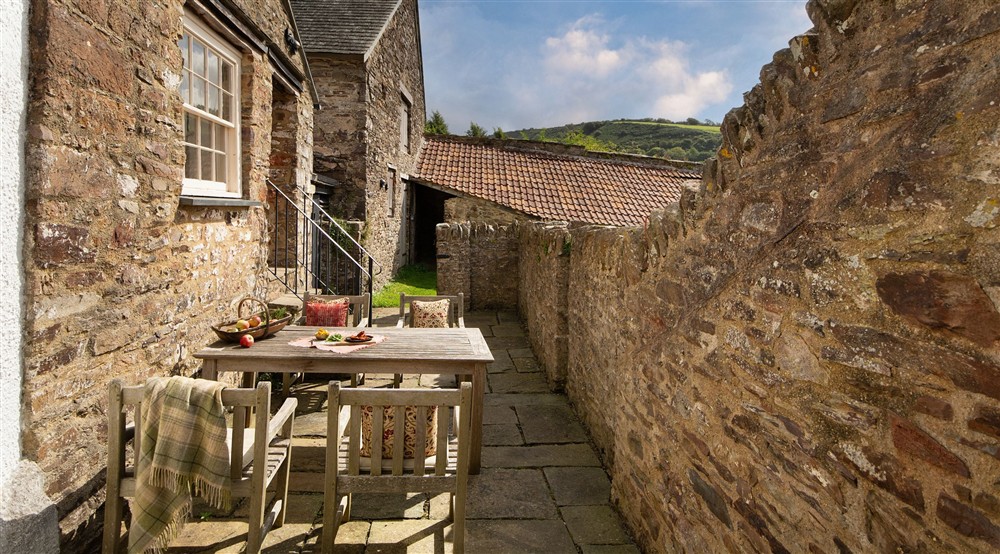 The terrace with outdoor dining furniture and main door to West Challacombe Manor, Devon at West Challacombe Manor in West Exmoor, Devon