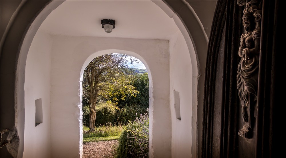The view of the front garden through the historic door and porch from the hallway at West Challacombe Manor in West Exmoor, Devon
