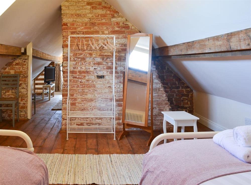 Charming attic bedroom with twin beds and exposed brickwork at West House Farm in Muston, near Filey, North Yorkshire