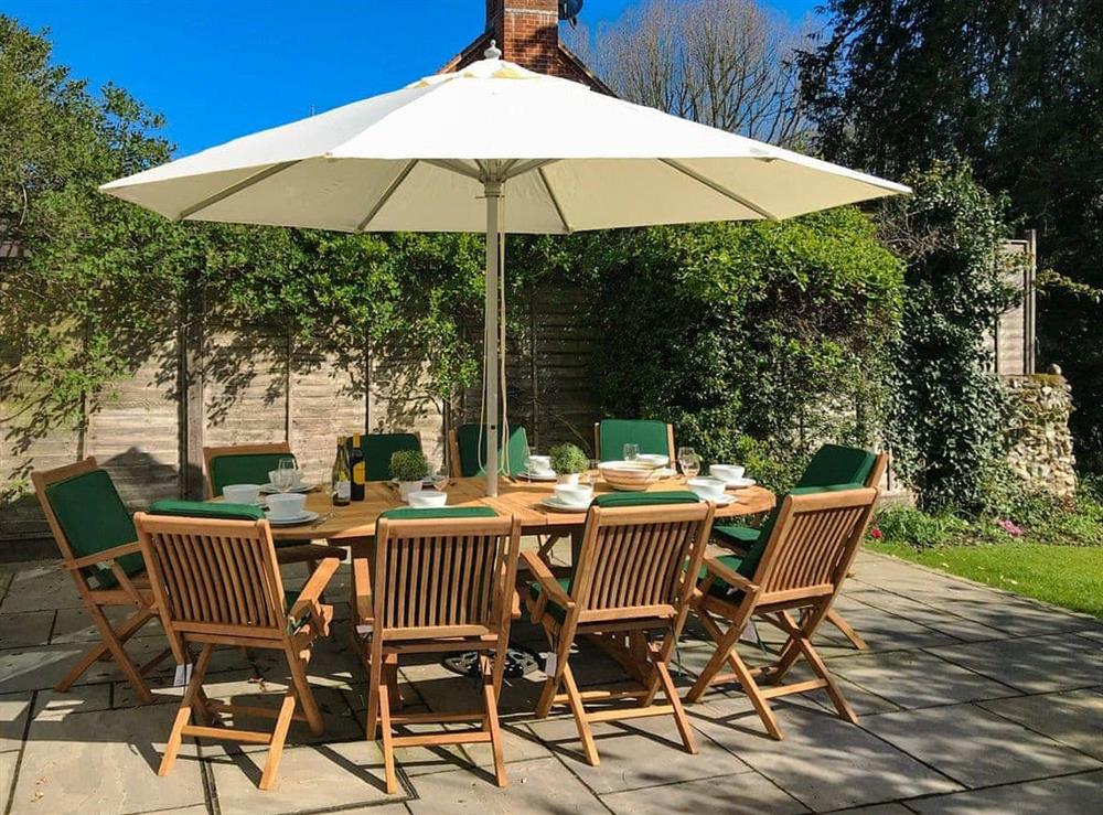 Paved patio with outdoor furniture overlooking the garden at White Horse Cottage in West Meon, near Petersfield, Hampshire