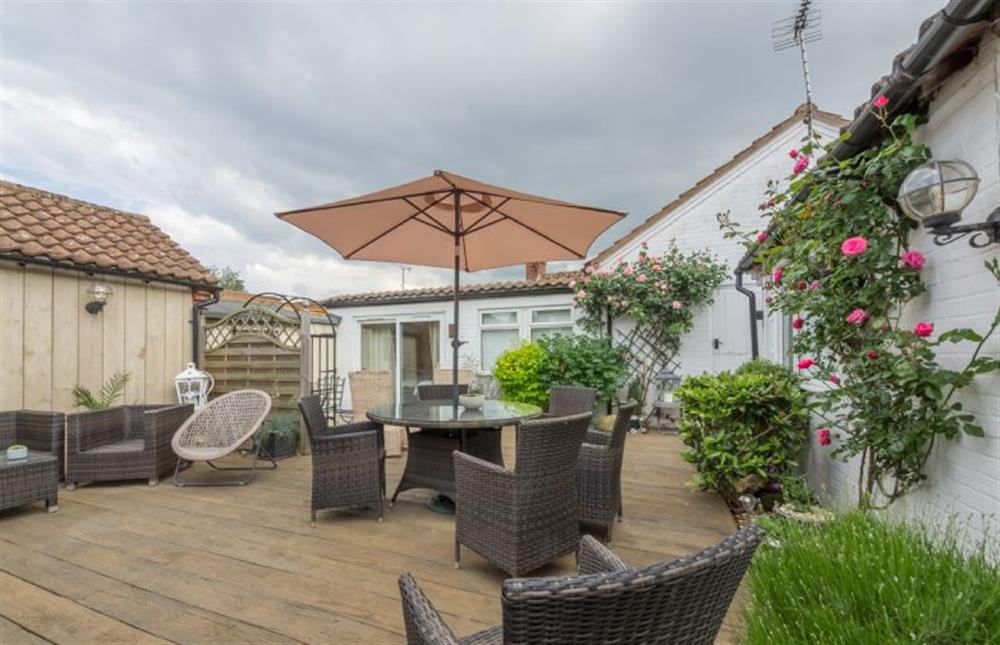 Fully-enclosed garden with decking area and comfortable seating at Whitehaven, Brancaster near Kings Lynn