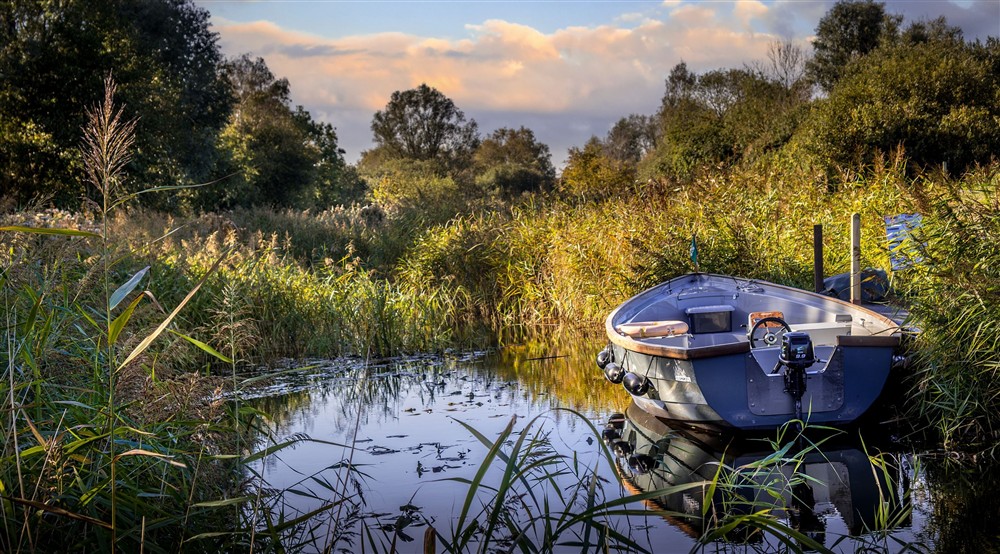 A boat moored on the Wicken Fen Nature Reserve, Cambridgeshire at Wicken Rose Cottage in Ely, Cambridgeshire
