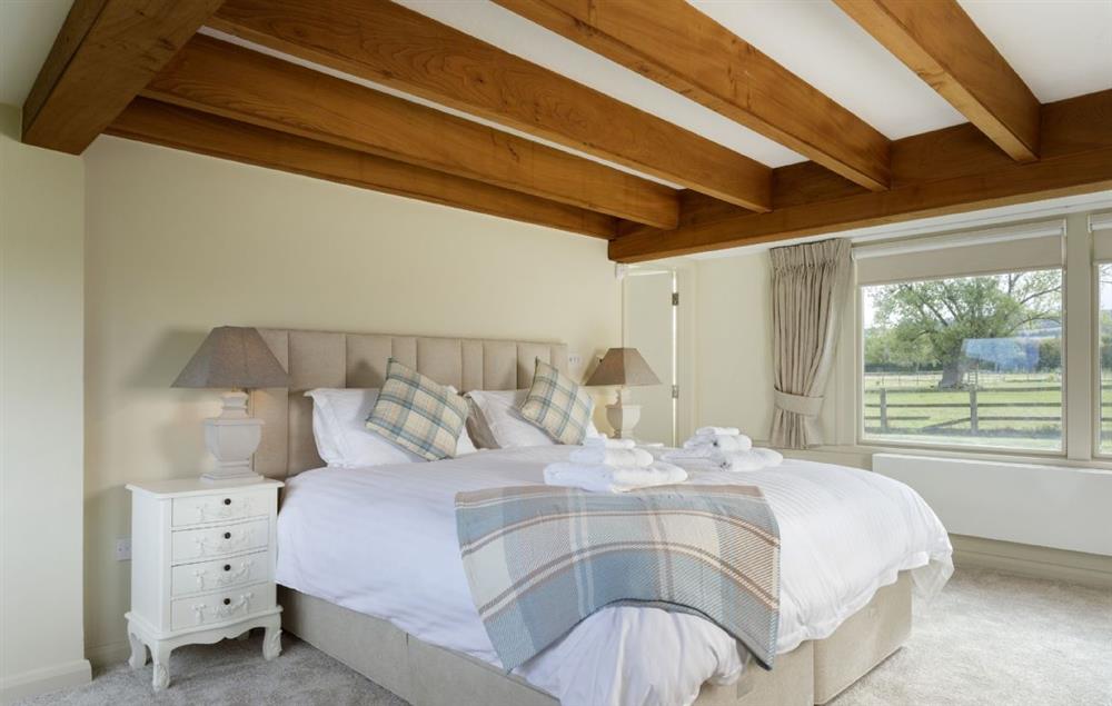 Bedroom one with a super-king bed and en-suite bathroom at Willersey Farm House, Willersey