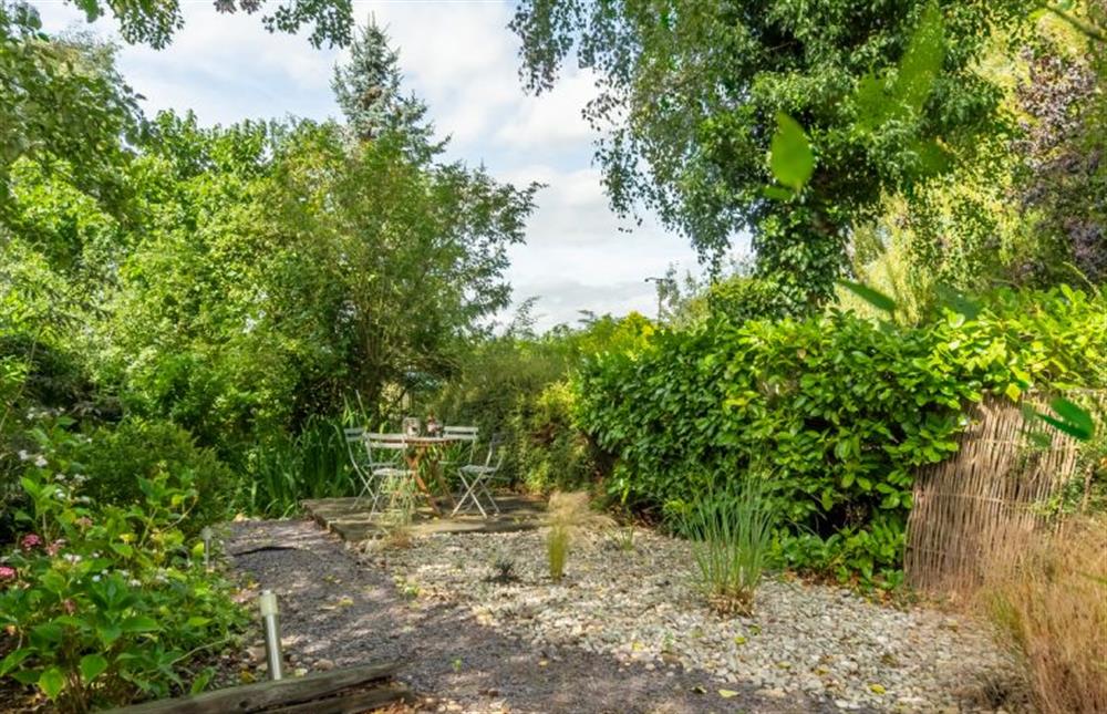 Beyond the enclosed garden is a little seating area next to the river Burn at Willow Cottage, North Creake near Fakenham