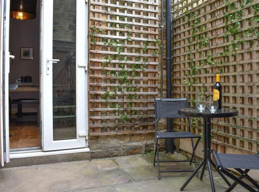 Compact courtyard garden with table and chairs at Windy Dales Cottage in Skipton, Yorkshire, North Yorkshire