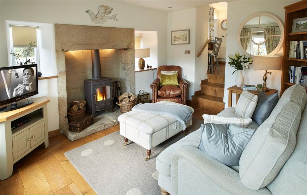 The sitting room with comfortable leather sofas and wood burning stove at Winsmore Cottage, Over Haddon