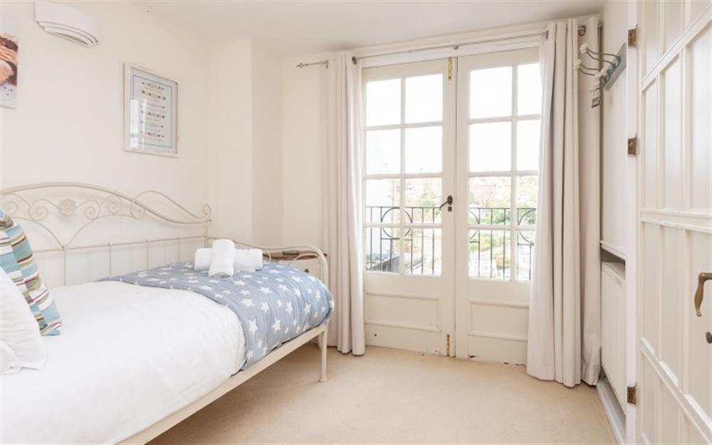 Bedroom 4 with with doors to a juliet balcony and views across Dartmouth to the River Dart. at Wisteria House in Dartmouth