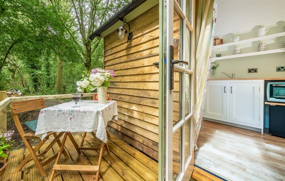 The wooden deck with garden table and chairs  at Woodland Retreat Shepherds Hut, Brundish