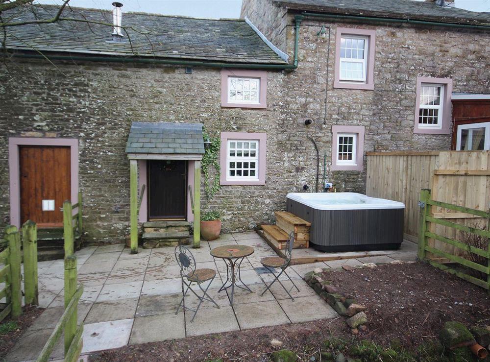 Right outside the back door sits the hot tub next to the sitting out area at Woodpecker Cottage in Wigton, Cumbria