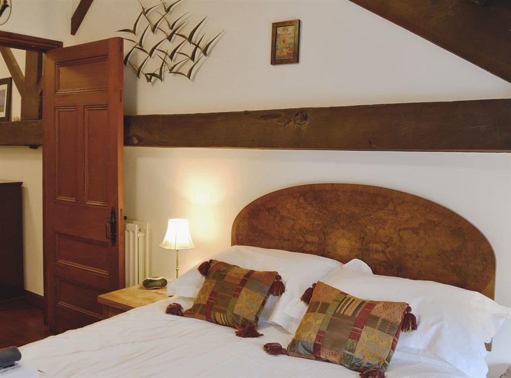 The beamed double bedroom features sloping ceilings at Woodpecker Cottage in Wigton, Cumbria