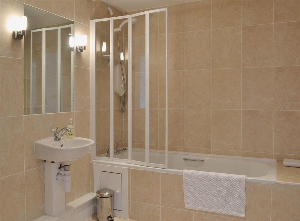 Large fully tiled family bathroom with shower over the bath at Y Stabl in Bethlehem, Carmarthenshire