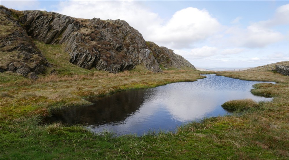 View of lake stretching into distance with rocky hill to on side at Y Wenallt in Beddgelert, North Wales