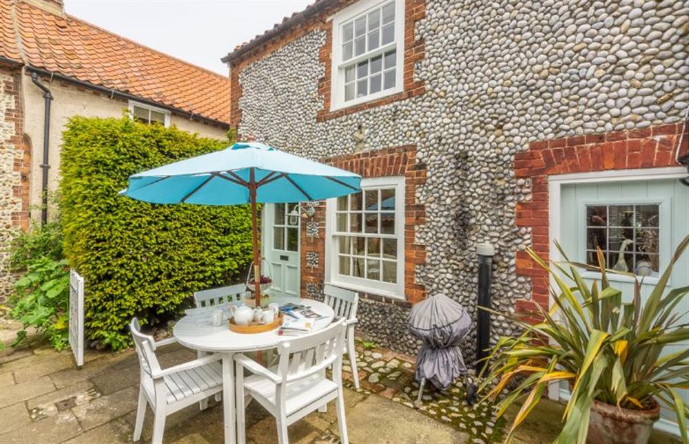 Enclosed courtyard garden with garden furniture and barbecue at Yew Tree Cottage, Blakeney near Holt