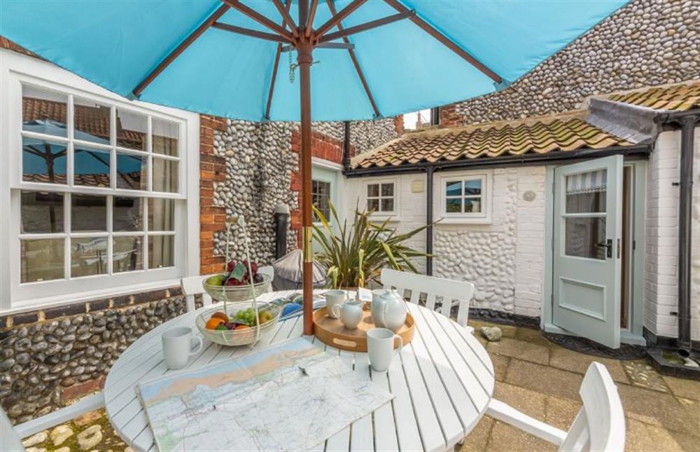Enclosed courtyard garden with table and seating for four at Yew Tree Cottage, Blakeney near Holt